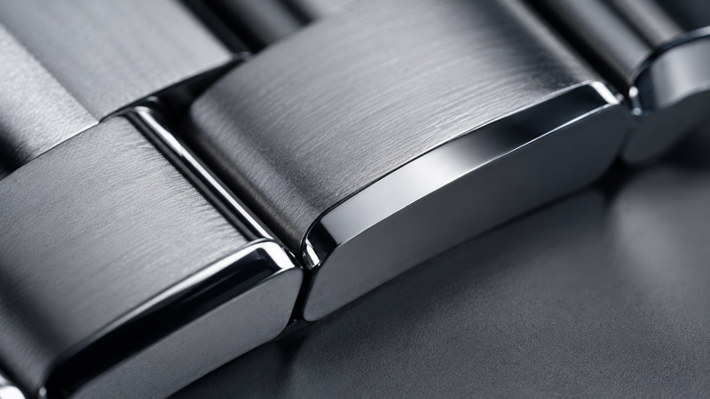 An ultra high definition macro shot focusing on the transition between brushed and polished surfaces of a luxury metal bracelet to show the pristine results of learning how to clean stainless steel watch strap links safely